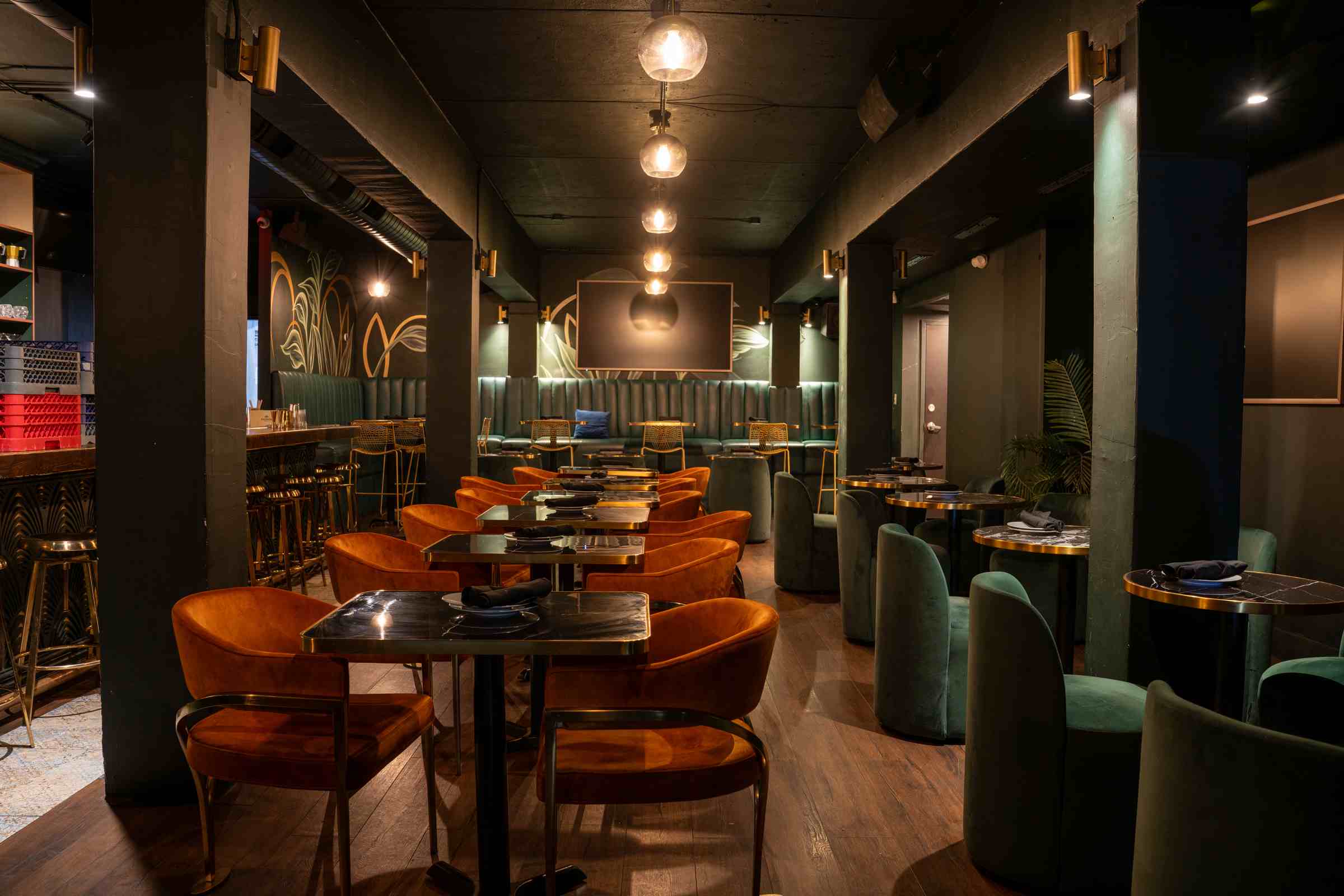 Brass-trimmed tables and rust velvet chairs under warm pendant lights at Spanglish Martini Bar, an upscale bar in Wynwood, Miami