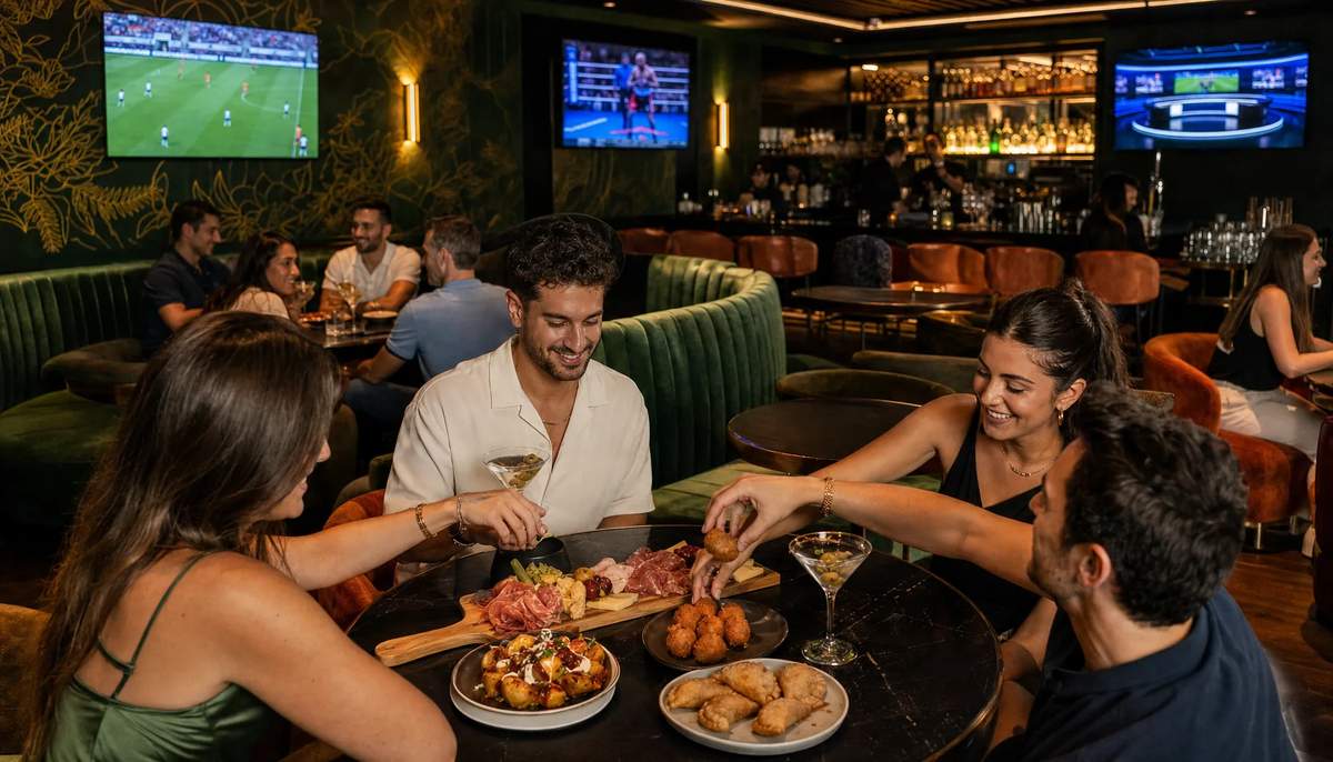 Friends reaching into a table of tapas plates with three martinis at Spanglish Martini Bar in Wynwood, Miami
